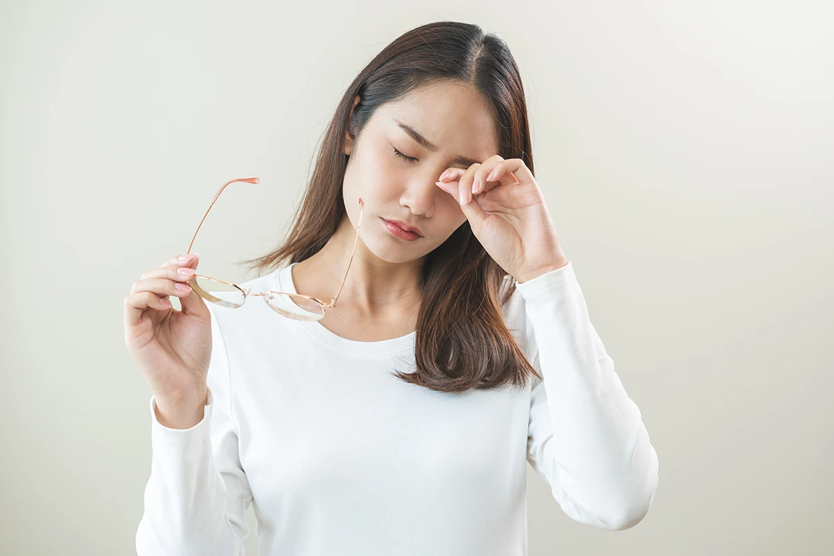 a woman taking off her glasses and rubbing her eye